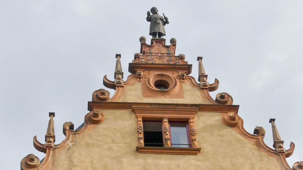 Statue des Winzers auf dem Giebel des Hauses.