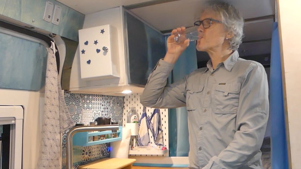 Marcus trinkt Wasser in der Wohnmobil-Küche.