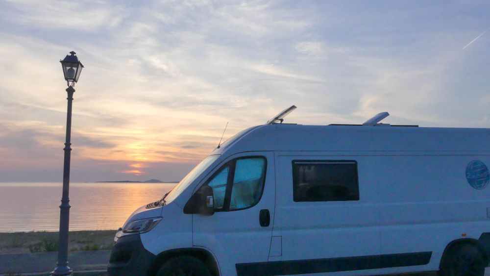 Wohnmobil vor Sonnenuntergang am Meer.