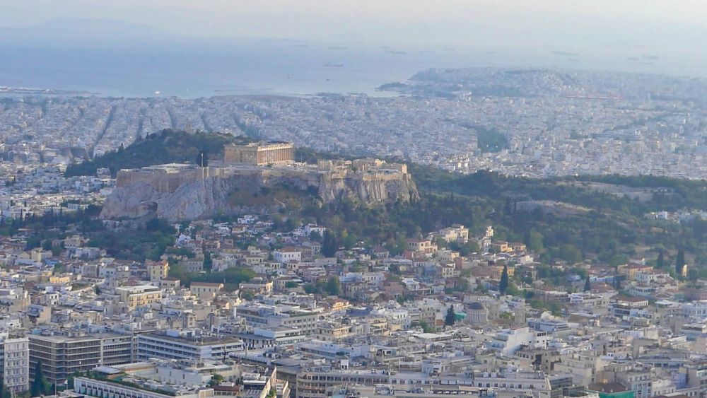 Blick auf den Akropolis-Hügel und die Stadt, im Hintergrund das Meer.