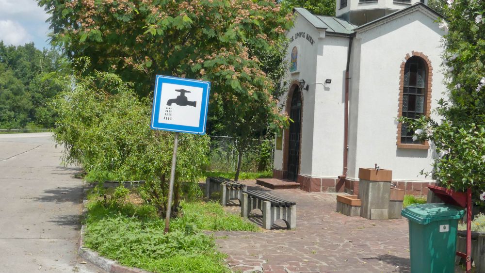 Schild mit Wasserhahn am Straßenrand.