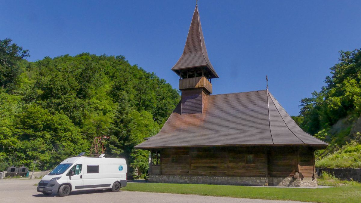 Wohnmobil steht vor Holzkirche in Rumänien.