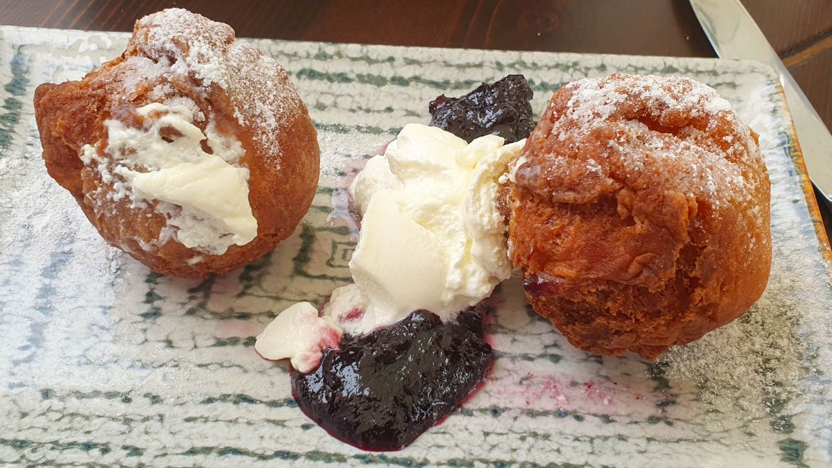 Zwei Quarkbällchen mit Schmand und Konfitüre.