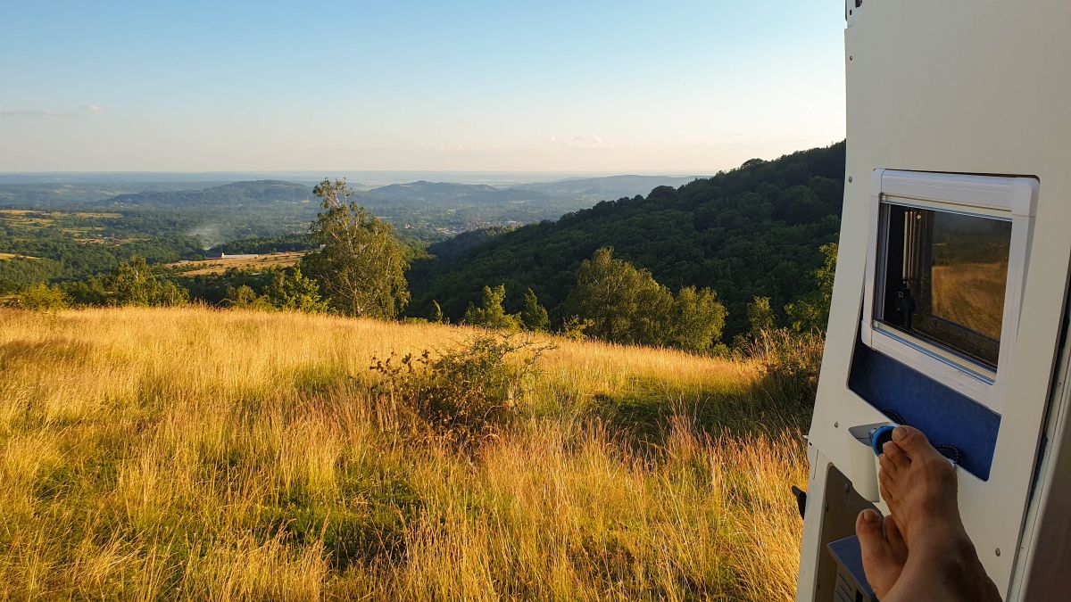 Blick aus der geöffneten Hecktür des Wohnmobils über die Berge.