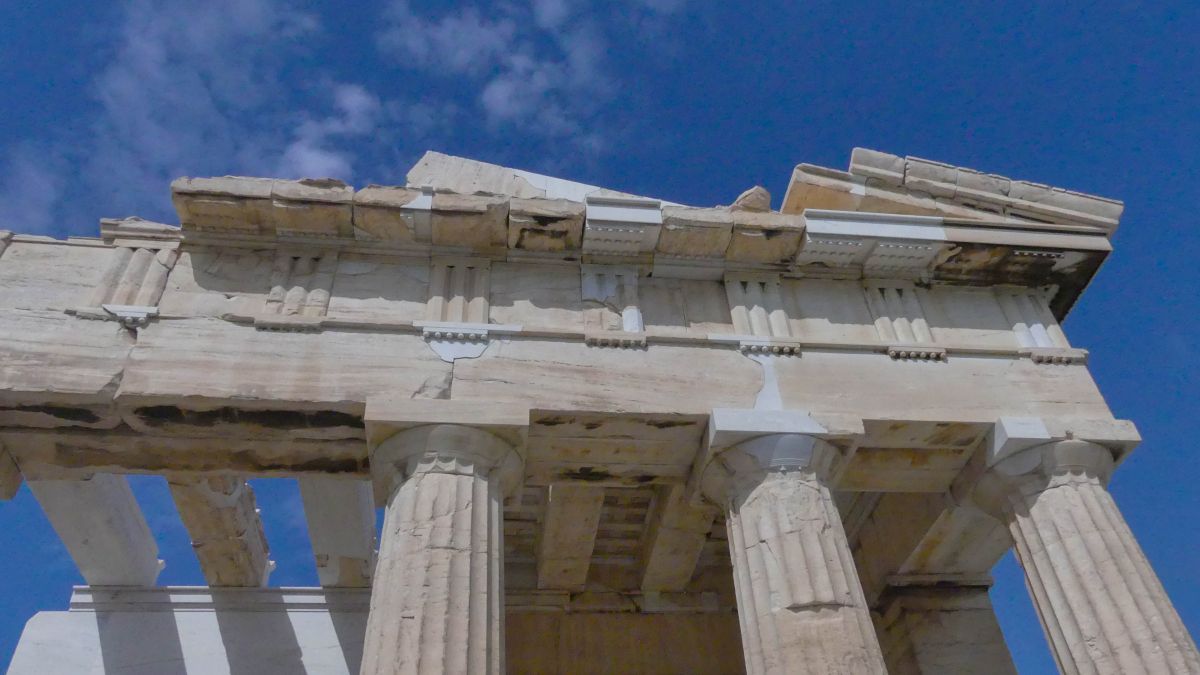 Giebel und Säulen des Parthenon vor blauem Himmel.