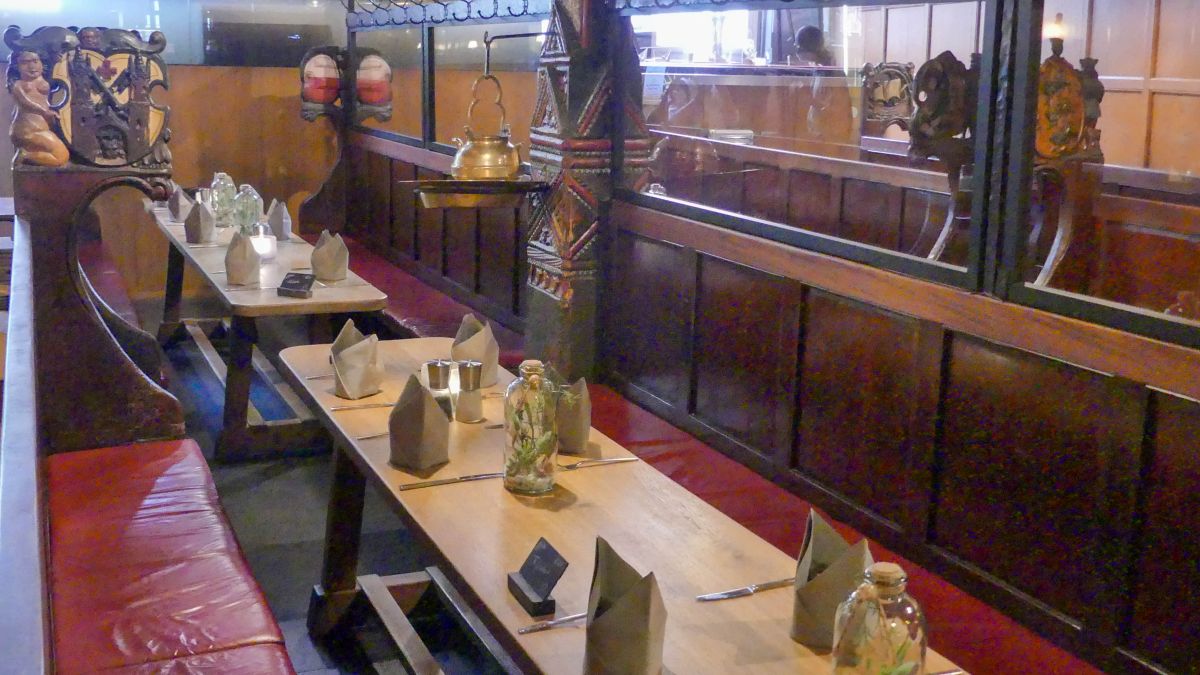 Lange Tische und Bänke im Inneren des Restaurants.