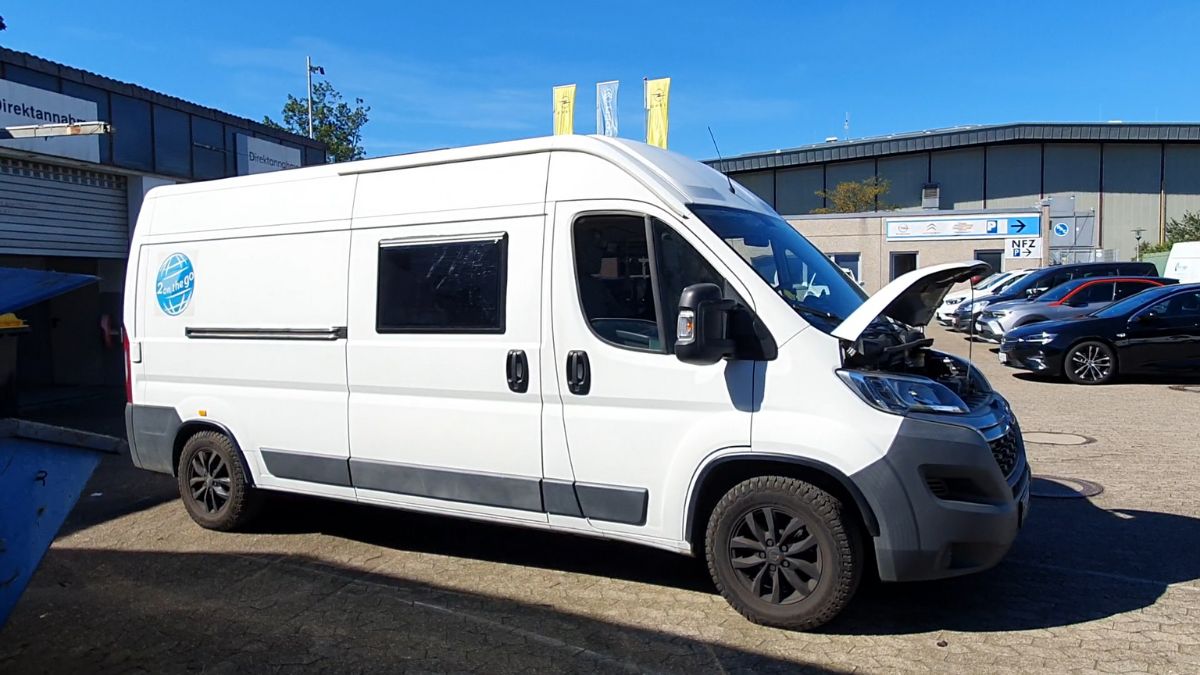 Der Van steht mit geöffneter Motorhaube vor der Werkstatt.