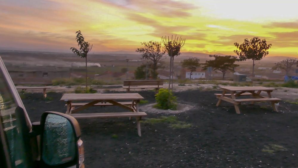 Sonnenuntergang über dem Tal, im Vordergrund Wohnmobil und Picknicktische.