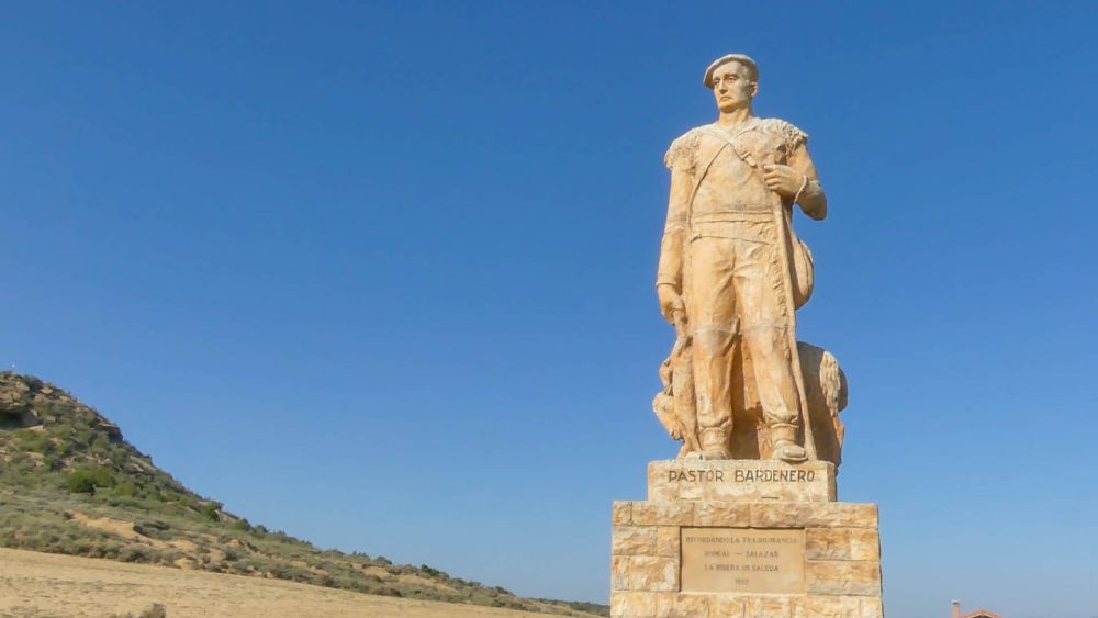 Sandfarbene riesige Skulptur eines Hirten.