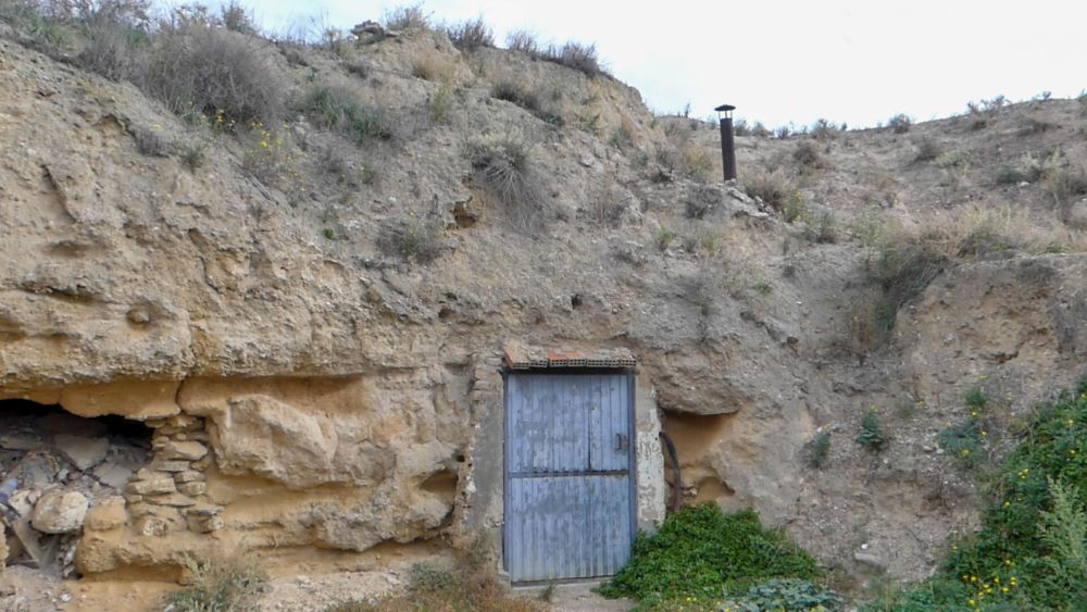Höhlenwohnung mit Tür und Kamin, der aus dem Fels ragt.