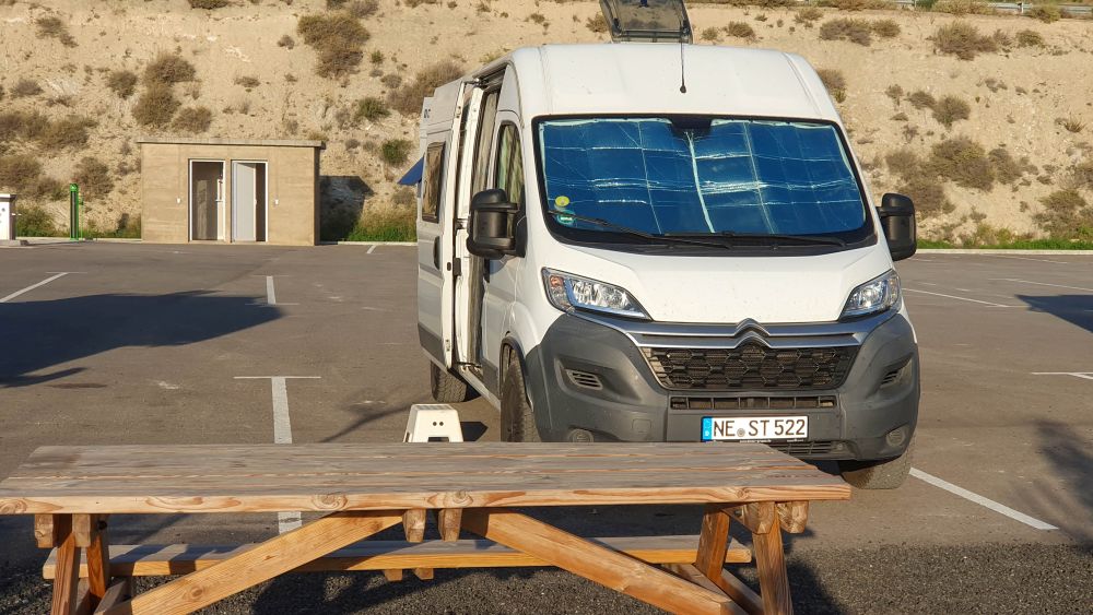 Wohnmobil steht auf einem asphaltierten Stellplatz, im Vordergrund ein Picknicktisch.