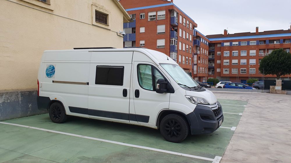 Wohnmobil steht auf einem Stellplatz, umgeben von Wohnhäusern.