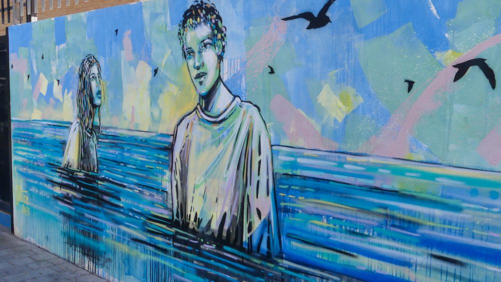 Mural, das zwei Menschen zeigt, die bis zum Bauch im Wasser stehen.