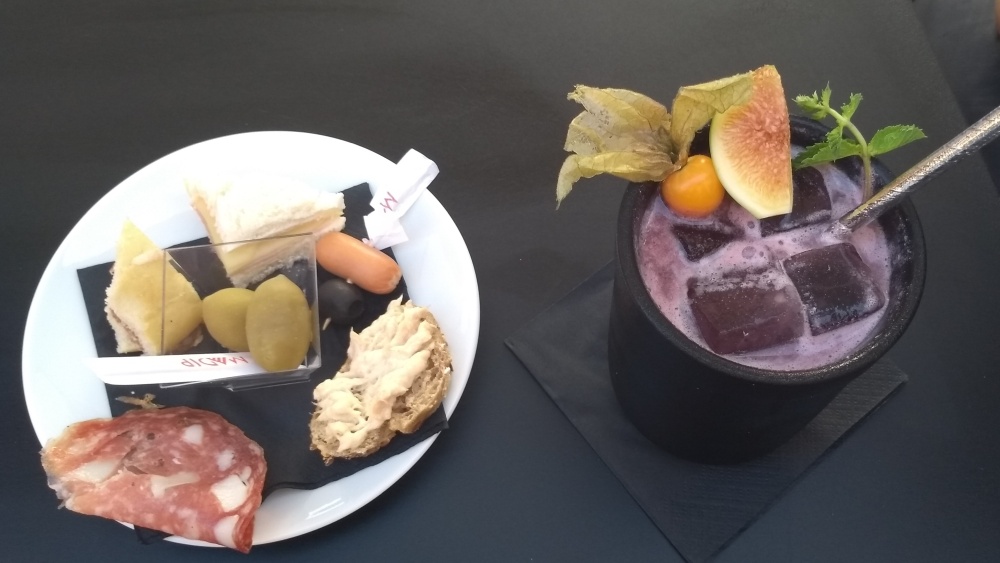 Aperitivgetränk und Teller mit kleinen Snacks.